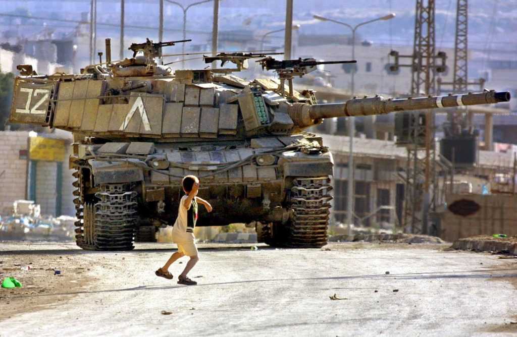 ¡A vencer y vivir! 1 niño palestino se enfrenta a un tanque israelí en la carretera del campo de refugiados palestinos de Daheisheh. 2 de julio 2002